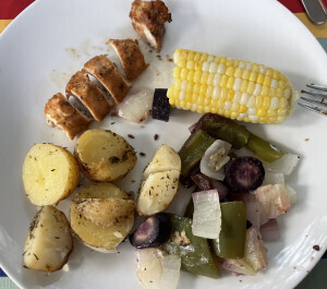 Plate with grilled chicken, corn on the cob, potates, green peppers, onion and carrots